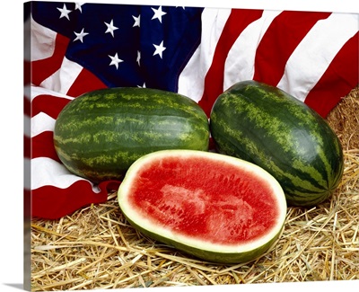 Whole and sliced watermelons on hay, with the American Flag