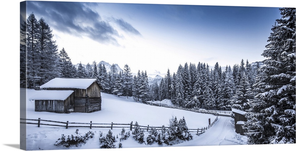 Winter scene looking down a country road at a log cabin surrounded by snow covered pine trees in Val Badia at the foot of ...