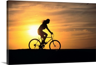 Woman Rides Mountain Bicycle Silhouetted At Sunset