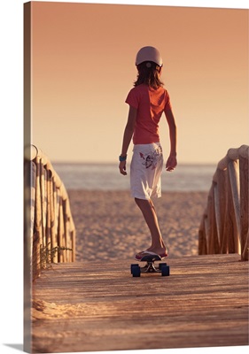 Young Person Skateboarding On A Wooden Boardwalk Towards Beach, Andalusia, Spain