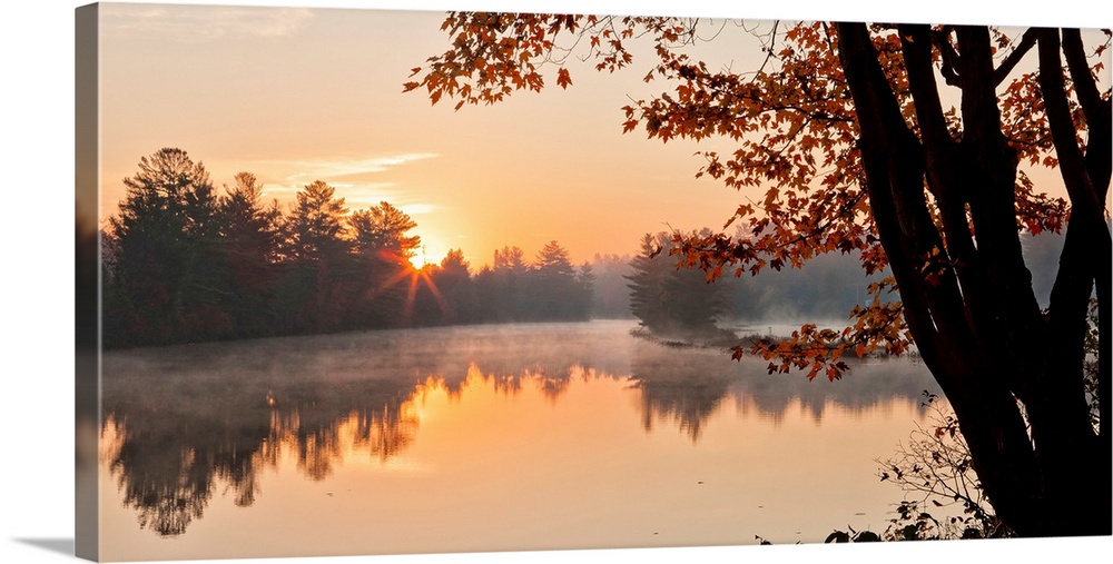 Big Canvas photo of a tranquil lake at sunrise with forests around it bathed in warm sunlight.