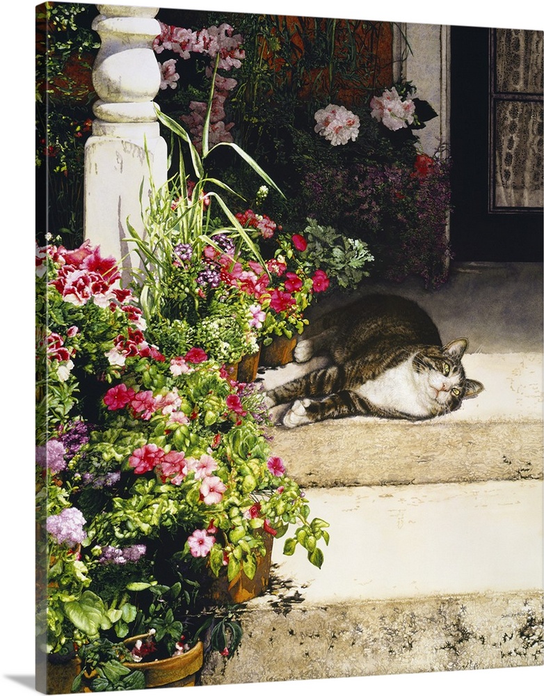 A vertical image of a tabby cat laying on a porch covered with flowers.