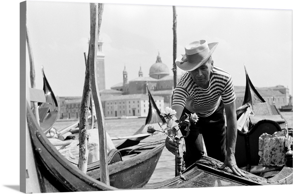 circa 1955:  A gondolier decorates his water taxi with roses