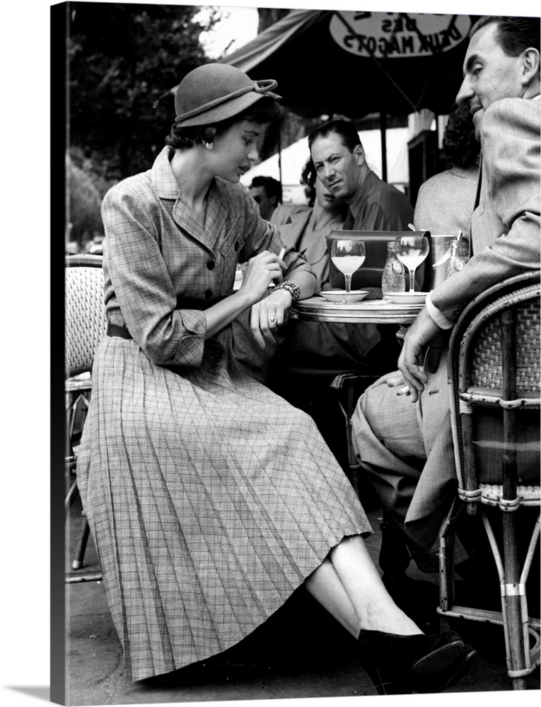 A Parisian woman wearing a mass-produced Norman Hartnell design, sits at a cafe in St Germaine des Pres, Paris These dress...