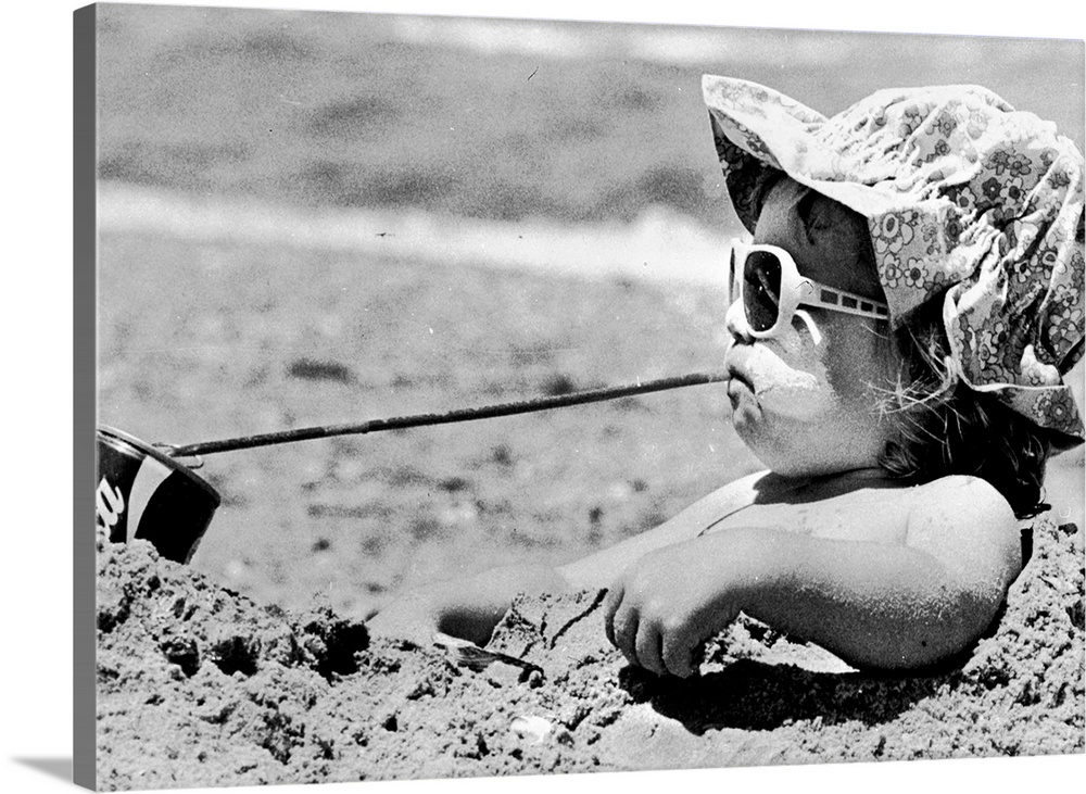 Danielle Martin enjoying a cold drink as she sits in a sand hole on the beach near Melbourne