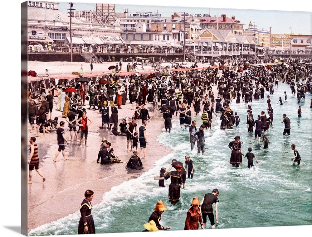 Horizontal, vintage photograph of a beach crowded with people in Atlantic City, New Jersey.  The boardwalk and buildings i...