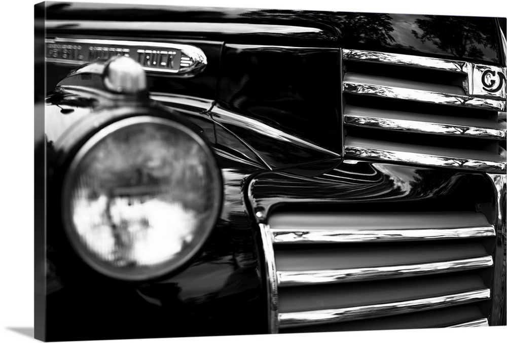 Black and white photo of the headlight and grille of a classic car.