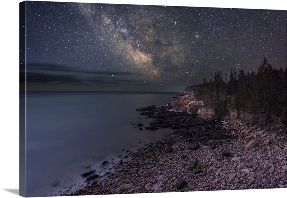 A photograph of a rocky beach under a starry night sky.