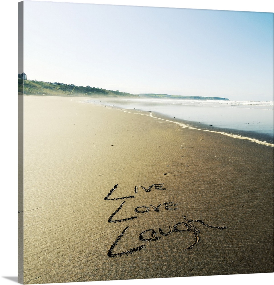 Photo of these words written in the sand: Live, Love, Laugh.
