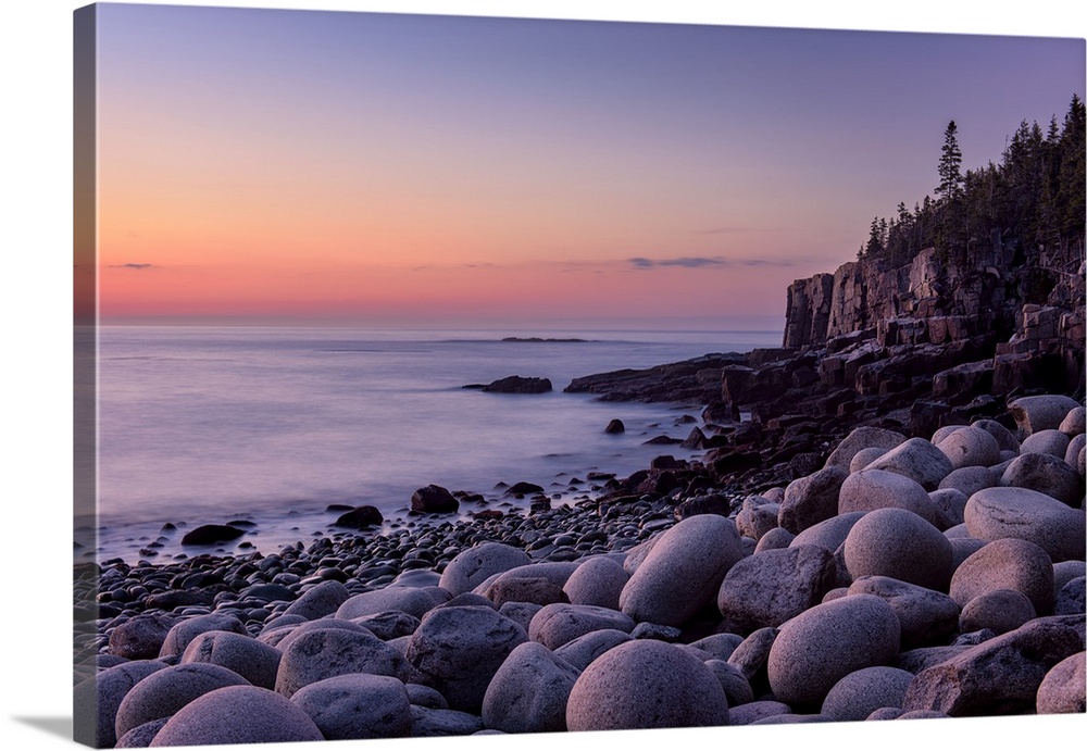 Landscape photograph of a rocky beach shore with a warm sunrise.