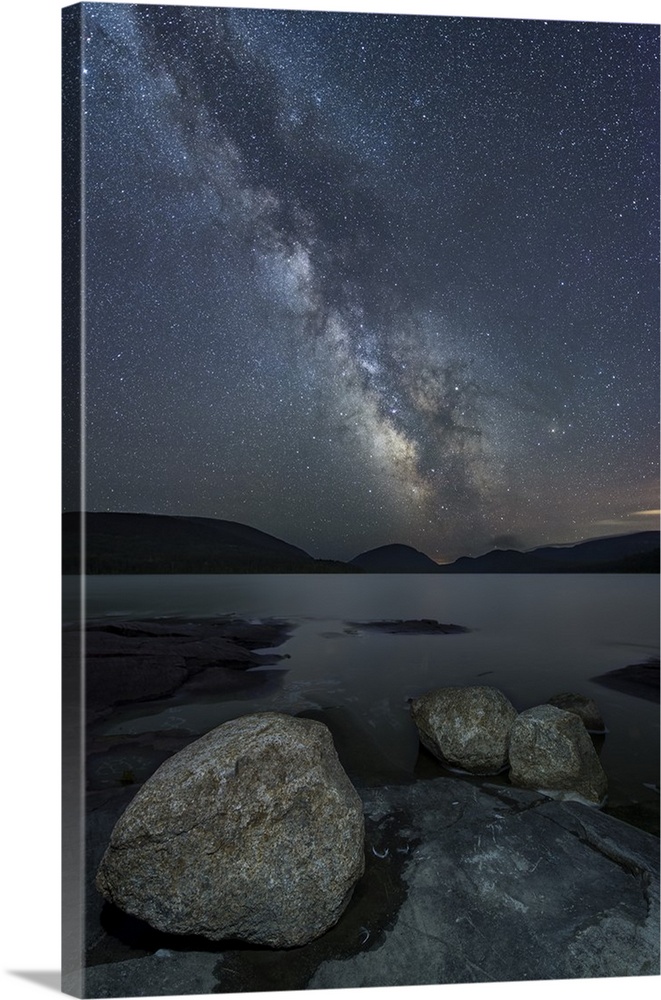 Photograph of Eagle Lake at night with boulders in the foreground and the Milky Way above in the night sky.