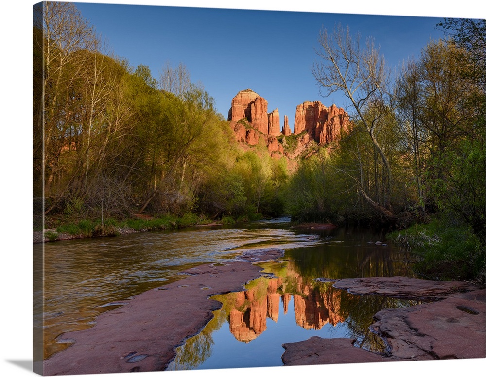 Landscape photograph of Cathedral Rock reflecting into a low, rocky river, Sedona AZ.