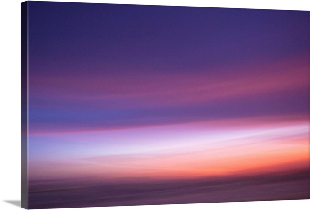 An artistic abstract photograph of a light purple and pink motion blurred cloudscape.