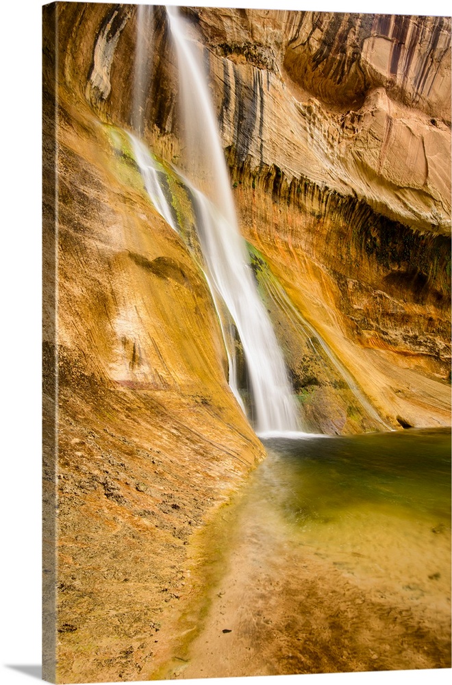 A photograph of a small waterfall streaming down a desert rock wall in an oasis.