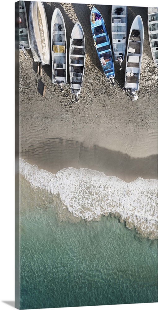 An artistic aerial photograph of a beach with rowboats sitting on the shoreline.