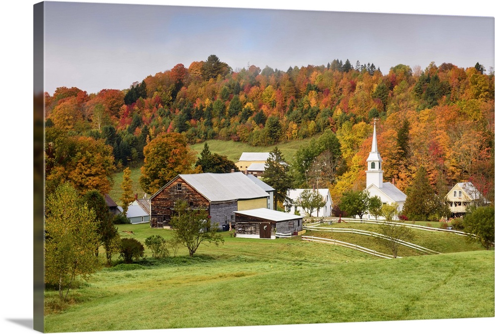 Landscape photograph of a hilly village with Fall trees and fog.