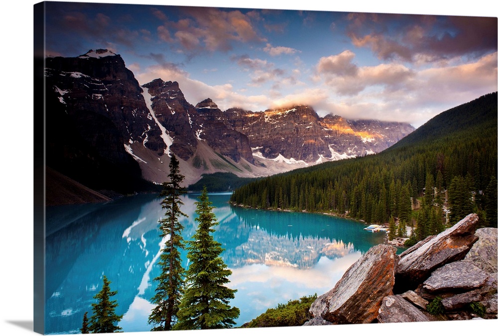 Landscape photograph of Lake Moraine surrounded bu snowy mountains and pine trees.