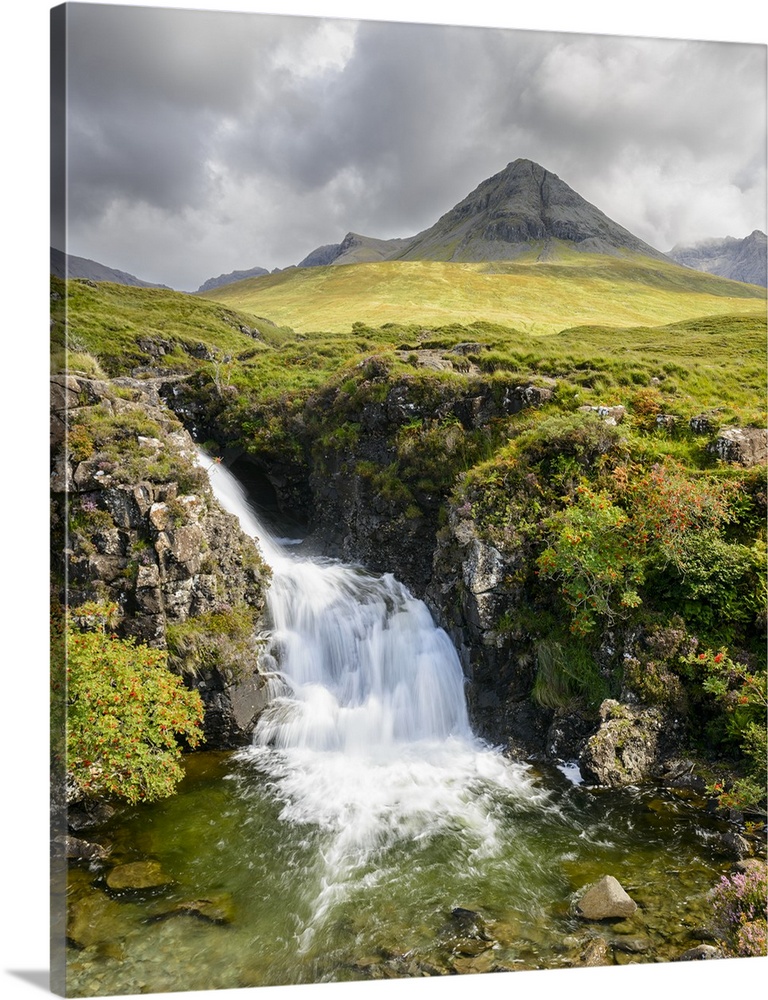 A photograph of a Scottish landscape with a mountain in the distance and a waterfall in the foreground.