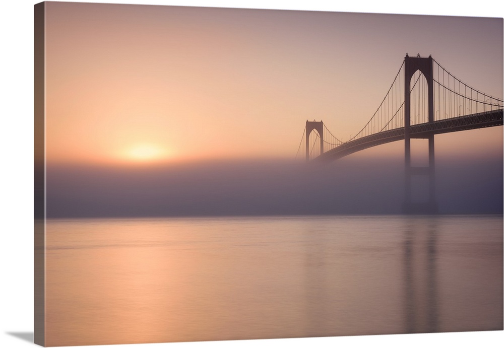 Beautiful photograph of the Golden Gate Bridge with heavy fog over the Bay and a warm sunrise.