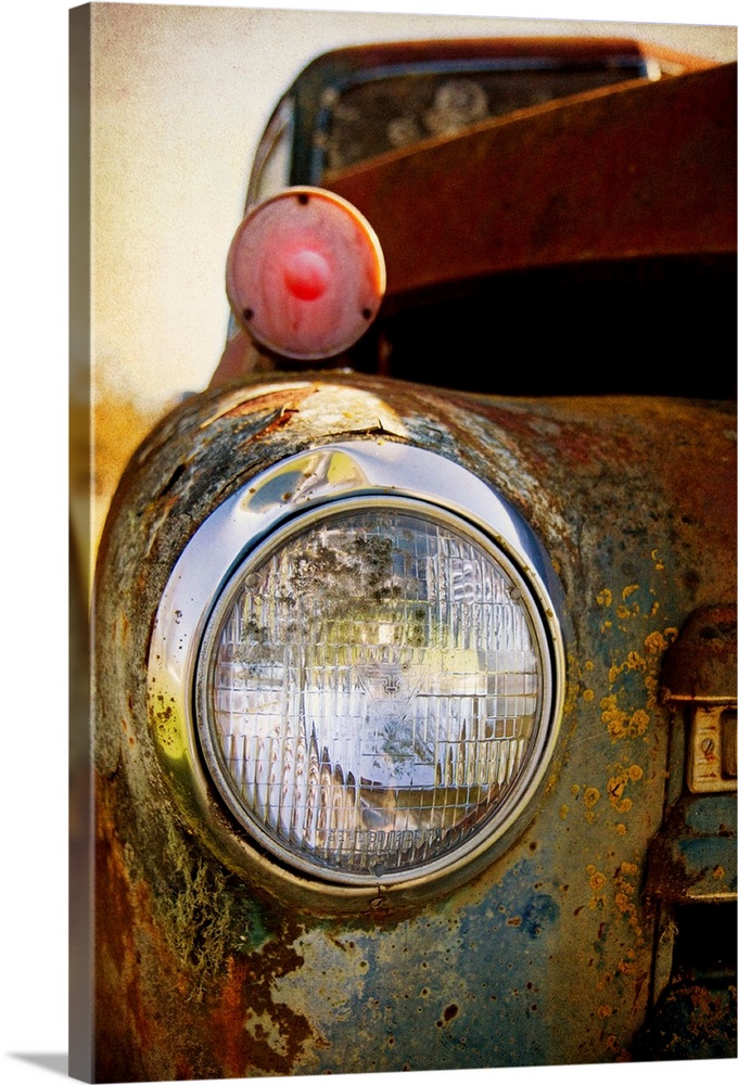 Photograph of a headlight of on the front of a vintage car.