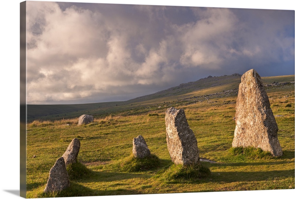 Standing stones in a grassy meadow with cloudy skies.