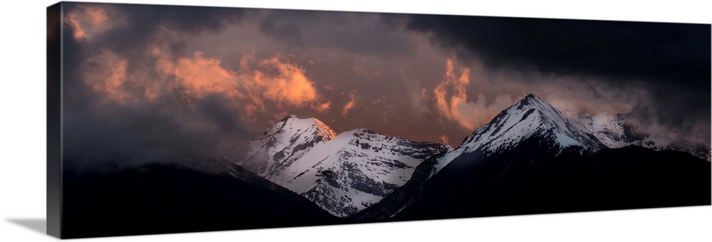 Landscape photograph of snowy mountain peaks at sunset.