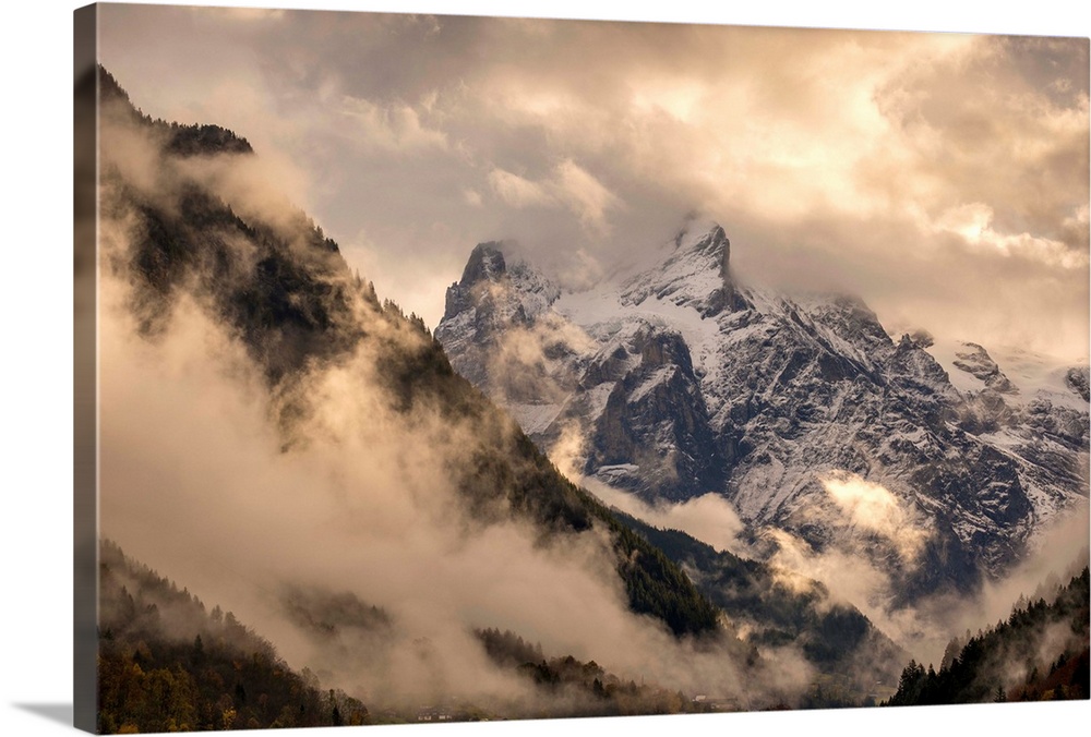 Beautiful landscape photograph of snowy mountain peaks engulfed in clouds.