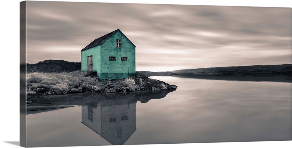 An artistic photograph of a mint colored shack at the edge of a shallow still river.