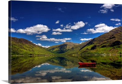 Red row boat on Placid Lake, with reflection of mountains in water