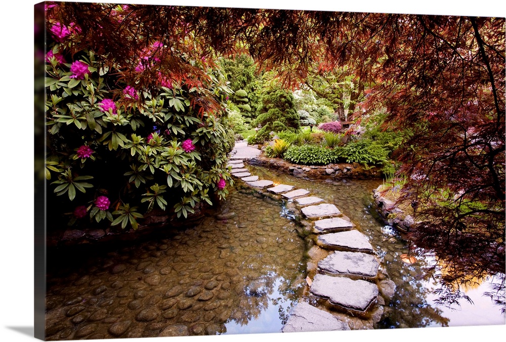 Photograph of stepping stones over water through a garden in bloom.