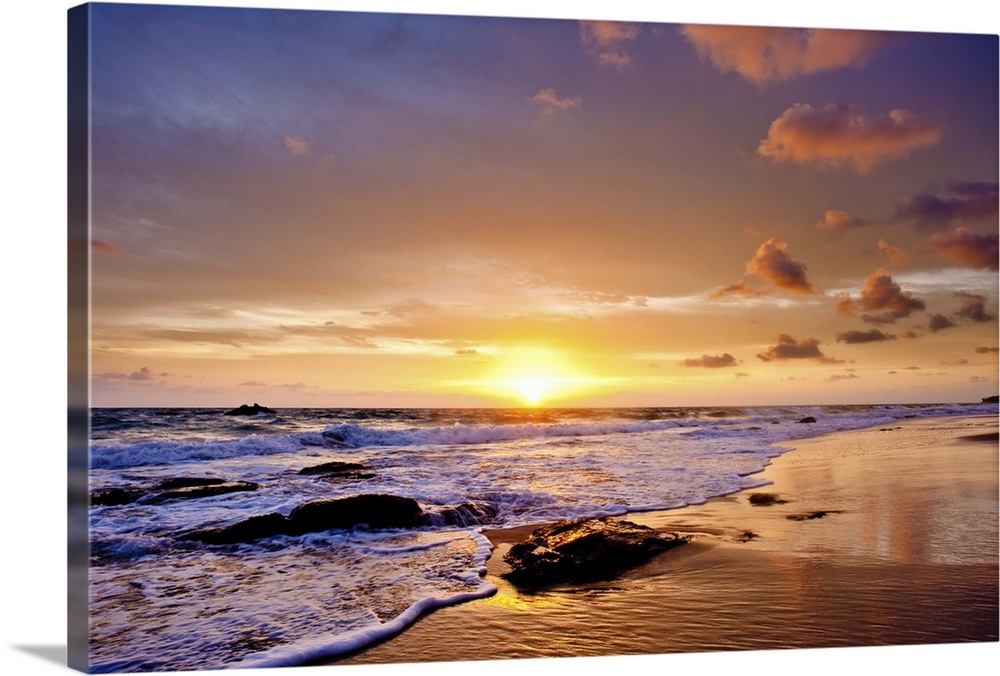 A photograph of a seascape seen from a beach at sunset.