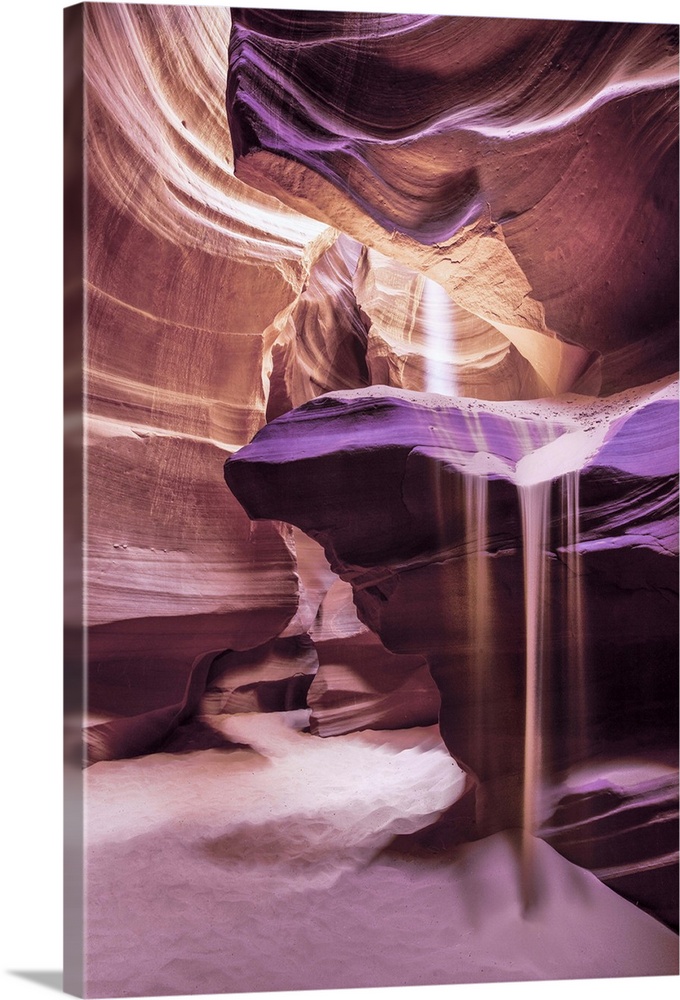 An artistic photograph of a slot canyon with a shaft of sunlight piercing the crevasse above.