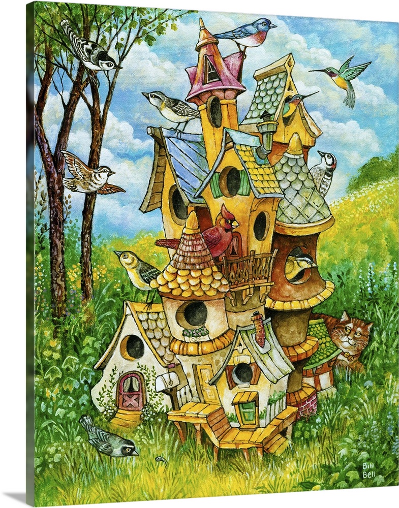 A large bird house with birds on it and a cat lying in the grass behind the house.