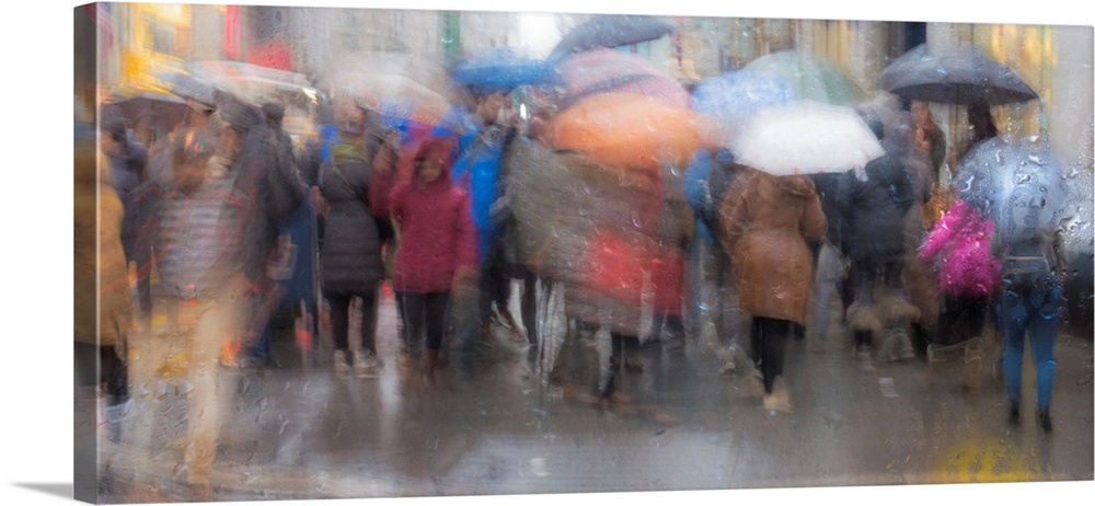 A contemporary slow shutter speed photograph of people walking with umbrellas in the rain