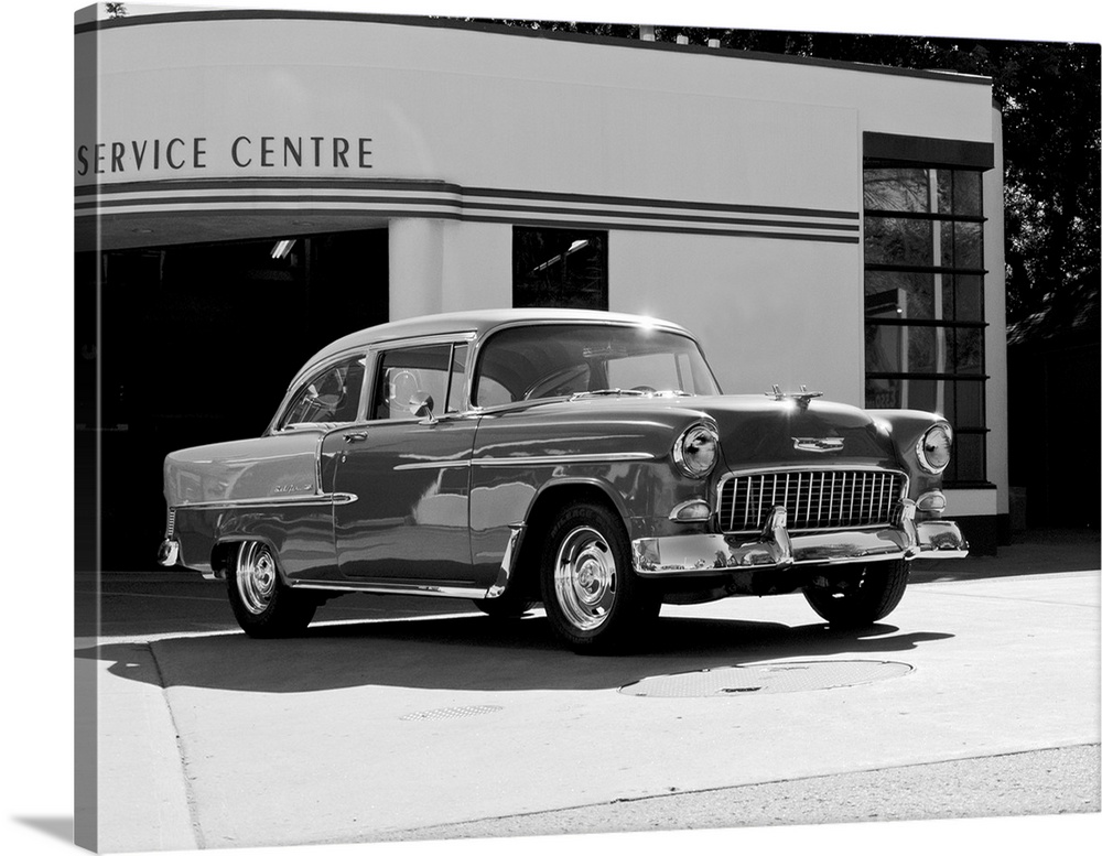Black and white photograph of a 1955 Chev Belair 7 in front of a service center.