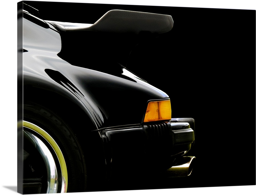 Photograph of the rear and back wing of a black 78 Porsche 930 with a solid black background.
