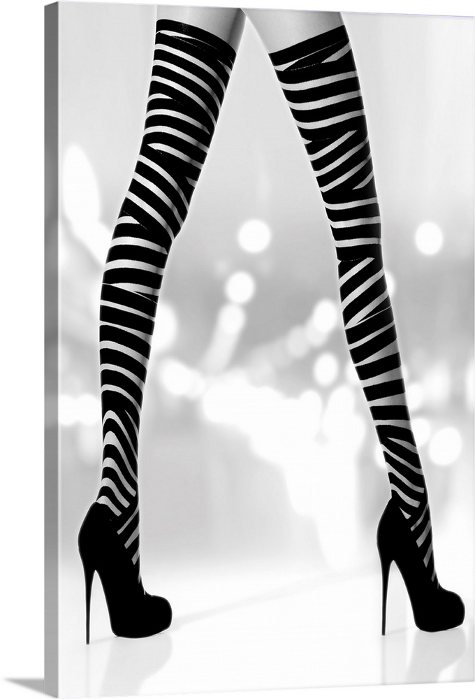 Black and white photograph of a woman's long legs with black high heels and striped stalkings.