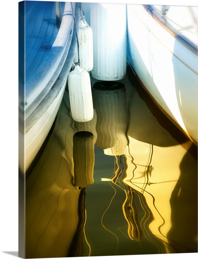 Photograph of two boats, side by side, reflecting into the golden lit water.