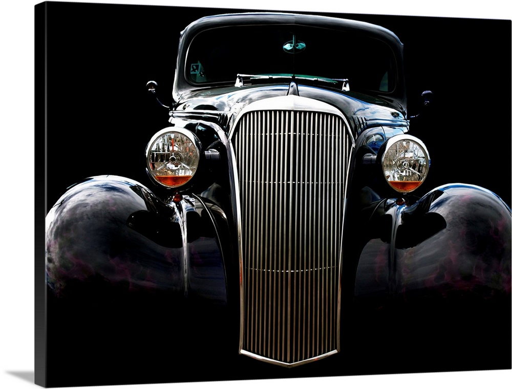 Photograph of the front of a black vintage Chevrolet with a solid black background.