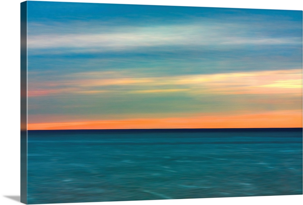 Horizontal image of a color sunset over calm ocean waters.