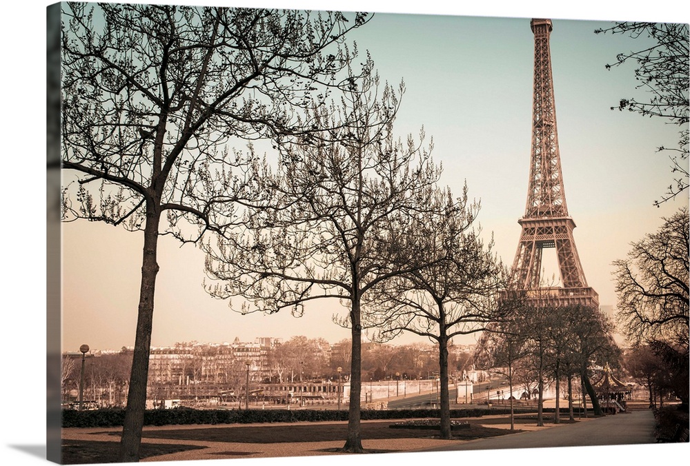 A muted colored photograph of the Eiffel Tower, viewed from a park sidewalk, in Paris, France.