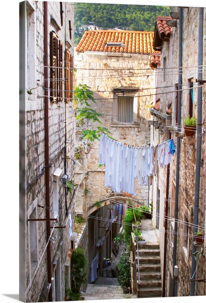 A narrow street leading down with steep steps, clothes lines hanging across the street, clothes hanging to dry Dubrovnik, ...