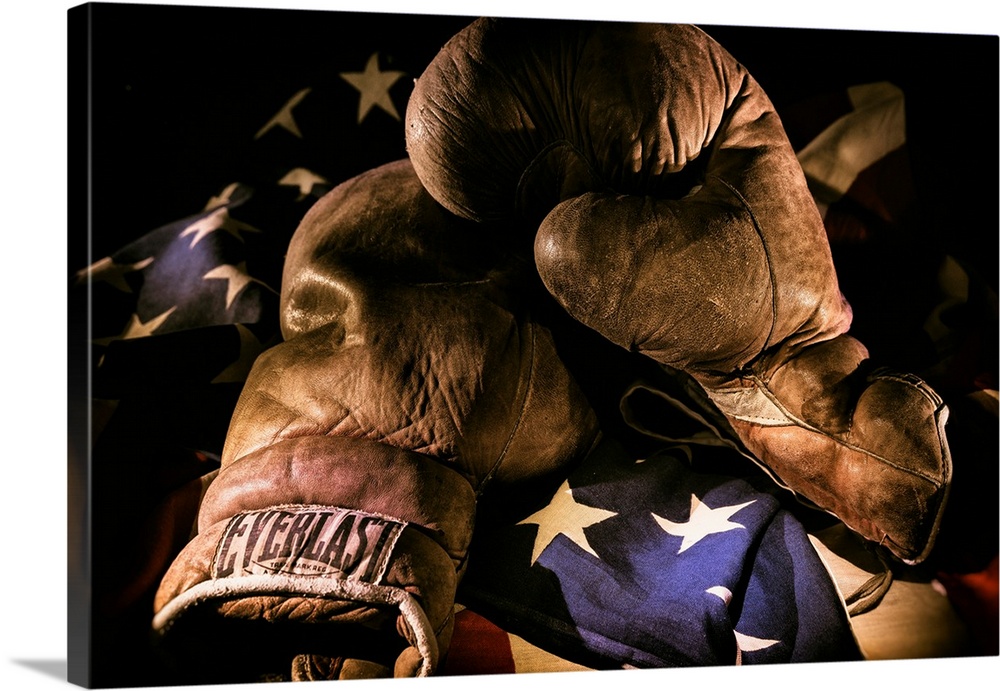 A pair of vintage boxing gloves laying on a flag carefully painted with light.