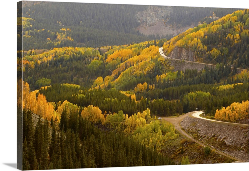 A road meanders through the brilliant fall colors of the San Juan Mountains of Colorado