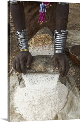 Africa, Ethiopia, Southern Omo, Karo Tribe.  Woman grinding grain into flour with stone.