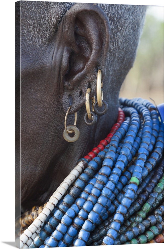 Africa, Ethiopia, Southern Omo Valley, Nyangaton Tribe.  An elderly Nyangton woman with four ear piercings and blue beads.