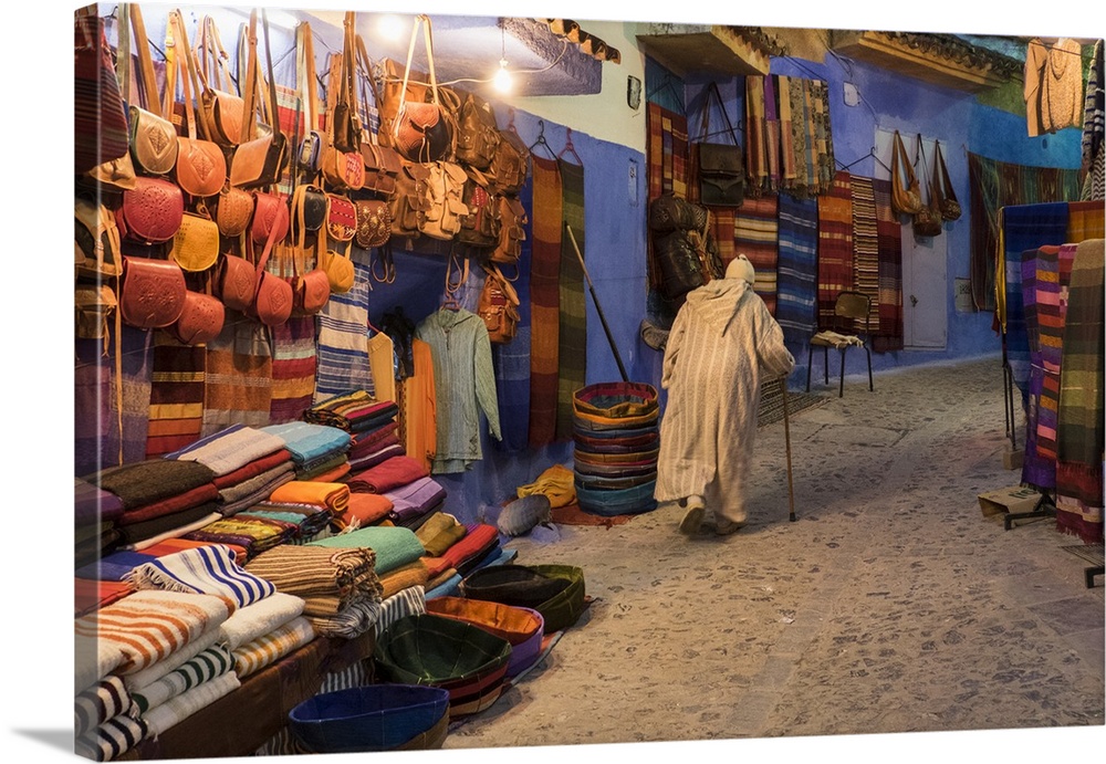 Africa, Morocco. An elderly man walks past tourist shops along a street in the blue city of Chefchaouen.