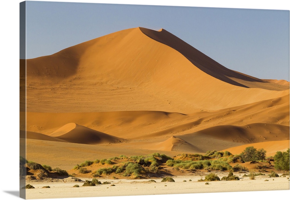 Africa, Namibia, Namib Desert, Namib-Naukluft National Park, Sossusvlei.  Large red dune rising from a while pan.