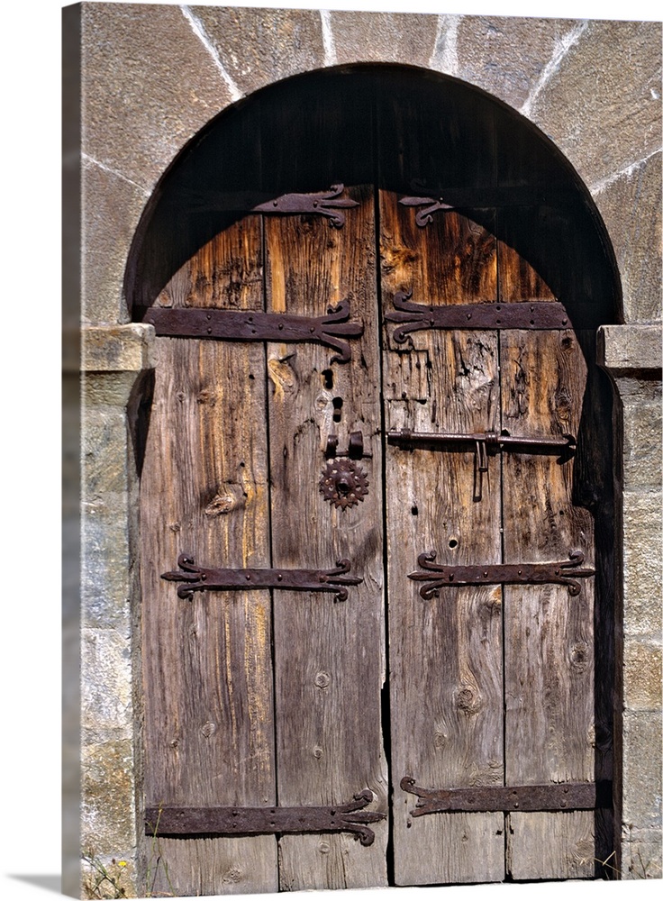 Europe, Andorra. An ancient old wooden door contrasts against a stone building in Andorra.