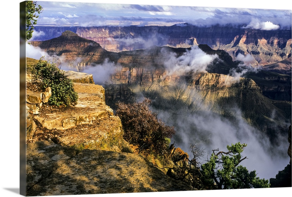 USA, Arizona, Grand Canyon National Park, North Rim, Sun shines on rim edge with clouds in the canyon at Cape Royal